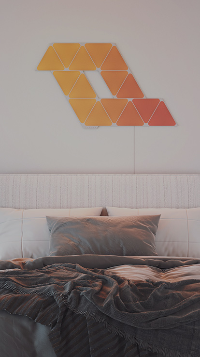 Dies ist ein Bild eines 5-Panel-Layouts der Nanoleaf Shapes Triangles an der Wand über dem Bett. Diese intelligenten Light Panels sind perfekt als Schlafzimmerbeleuchtung und für die Schaffung der perfekten Atmospähre.