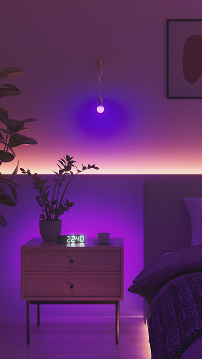 Questa è un’immagine di una lampadina Nanoleaf Essentials in una camera da letto. L’installazione luminosa è posizionata sulla parete tra il letto e il comodino e costituisce la luce da camera da letto perfetta per creare l’atmosfera ideale.
