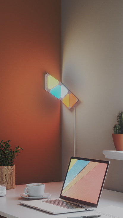 This is an image of a 5 panel layout of Nanoleaf Shapes Mini Triangles over a desk. The design bends around the corner of the desk using flex linkers. The smart lights are perfect for finding inspiration and boosting productivity while you work.