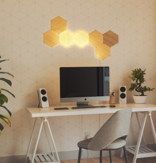 Dies ist ein Bild eines 7-Panel-Layouts aus Holzoptik Hexagons von Nanoleaf Elements an der Wand über einem Computer. Diese modularen, intelligenten Lichtpanels kreieren ein einzigartiges Design, das Ihre Umgebung mit einem natürlichen Licht beleuchtet. Die perfekte Beleuchtung für Ihr privates Büro.
