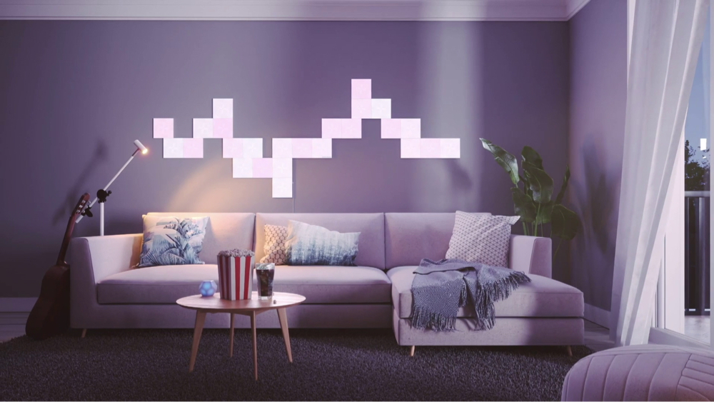 Questa è un’immagine di un soggiorno moderno e dall’atmosfera rilassata con quadrati luminosi Nanoleaf Canvas dietro il divano. I pannelli RGB che cambiano colore offrono oltre 16 milioni di brillanti colori vivaci e sono completamente personalizzabili grazie al layout modulare. Le luci del soggiorno perfette per creare l’atmosfera.