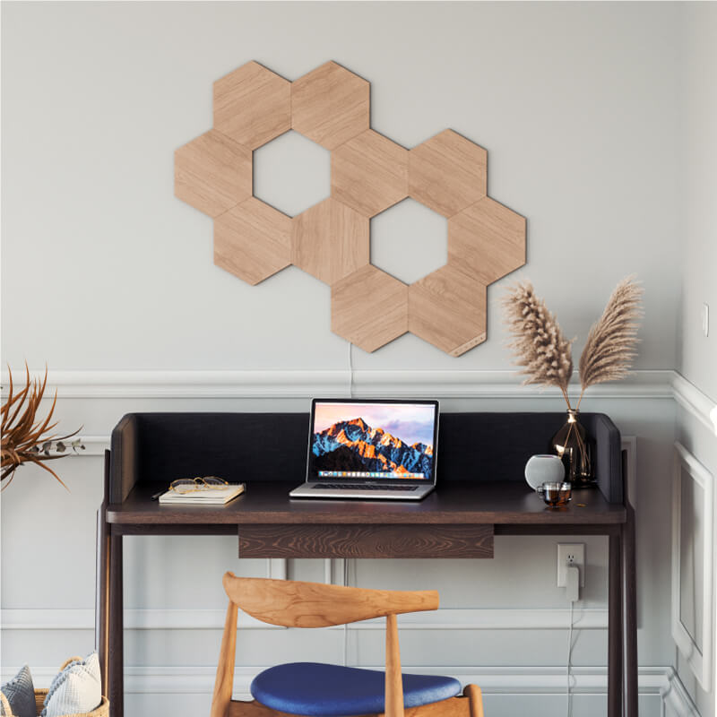 Nanoleaf Elements Hexagons in Holzoptik, Thread-kompatible, intelligente modulare Lichtpanels an einer Wand im Home-Office. HomeKit, Google Assistant, Amazon Alexa, IFTTT.