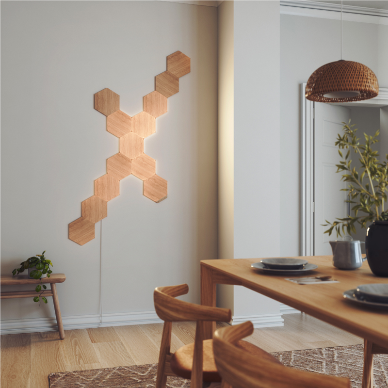 Pannelli luminosi esagonali smart modulari effetto legno Nanoleaf Elements compatibili con Thread montati sul muro di una sala da pranzo. App Nanoleaf. HomeKit, Assistente Google, Alexa di Amazon, IFTTT.