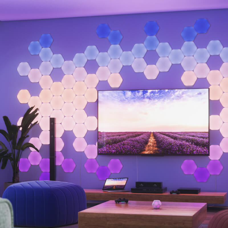 Panneaux lumineux modulaires intelligents hexagonaux Nanoleaf Shapes compatibles Thread montés sur un mur dans une salle de séjour. Semblables à Philips Hue, Lifx. HomeKit, Assistant Google, Amazon Alexa, IFTTT.